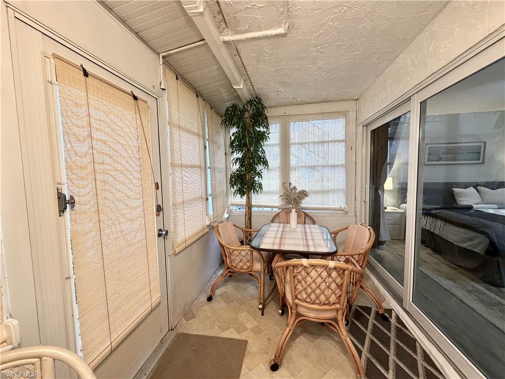 Enclosed lanai eating area with access to the primary bedroom with a back door to walk out to the grassy area behind the unit.