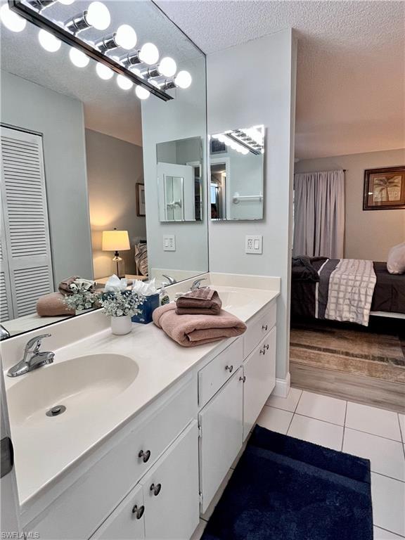Full bath featuring double vanity, closet, a shower stall, and light tile floors
