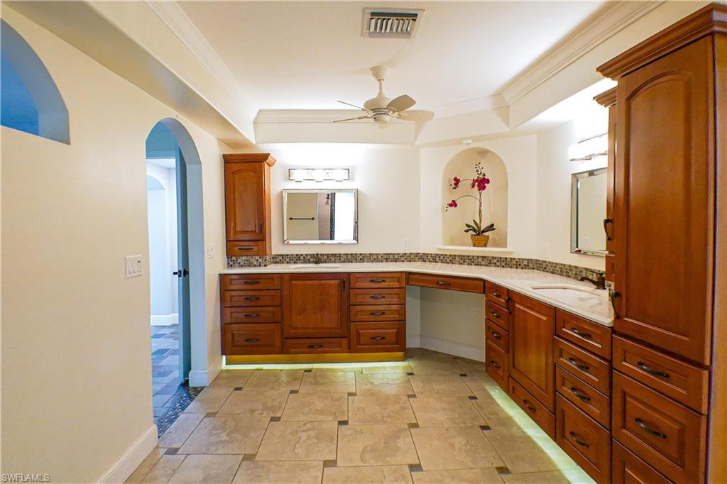 Unfurnished room with ceiling fan, ornamental molding, and arched walkways