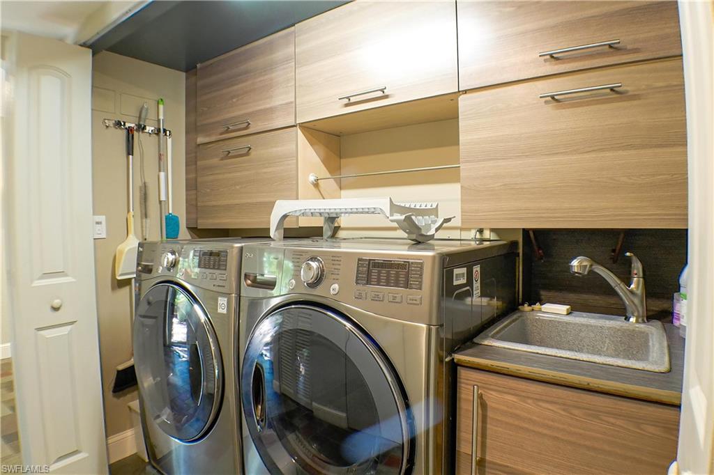 Laundry area with separate washer and dryer, arched walkways, and light stone finish flooring