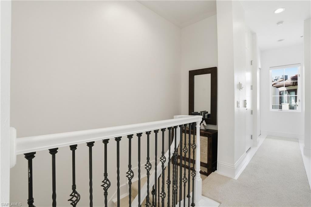 Hallway with light colored carpet and an upstairs landing