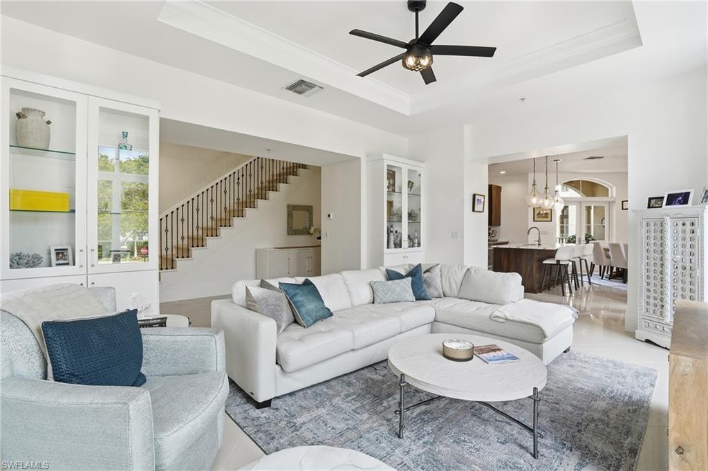 Living area featuring suspended lighting, ceiling fan, and a raised ceiling
