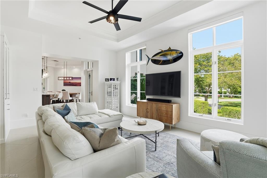 Living area featuring ceiling fan, tile patterned flooring, and a tray ceiling