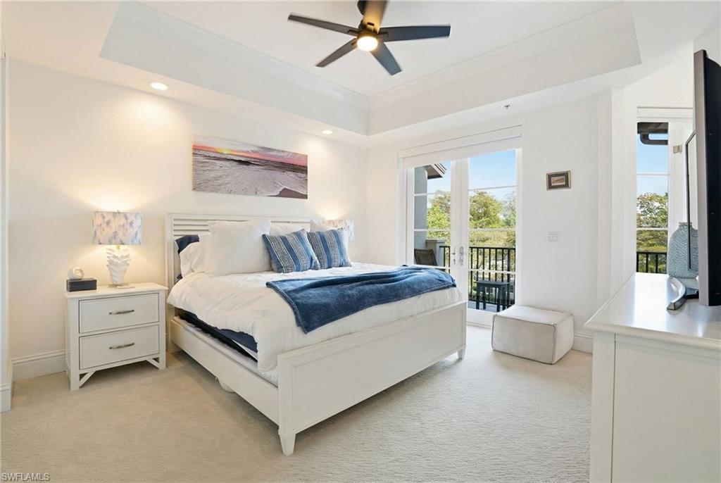 Bedroom featuring a tray ceiling, light colored carpet, access to outside, a ceiling fan, and crown molding