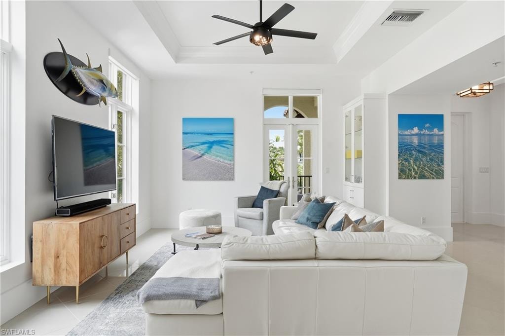 Living room with ceiling fan, light tile patterned flooring, and crown molding