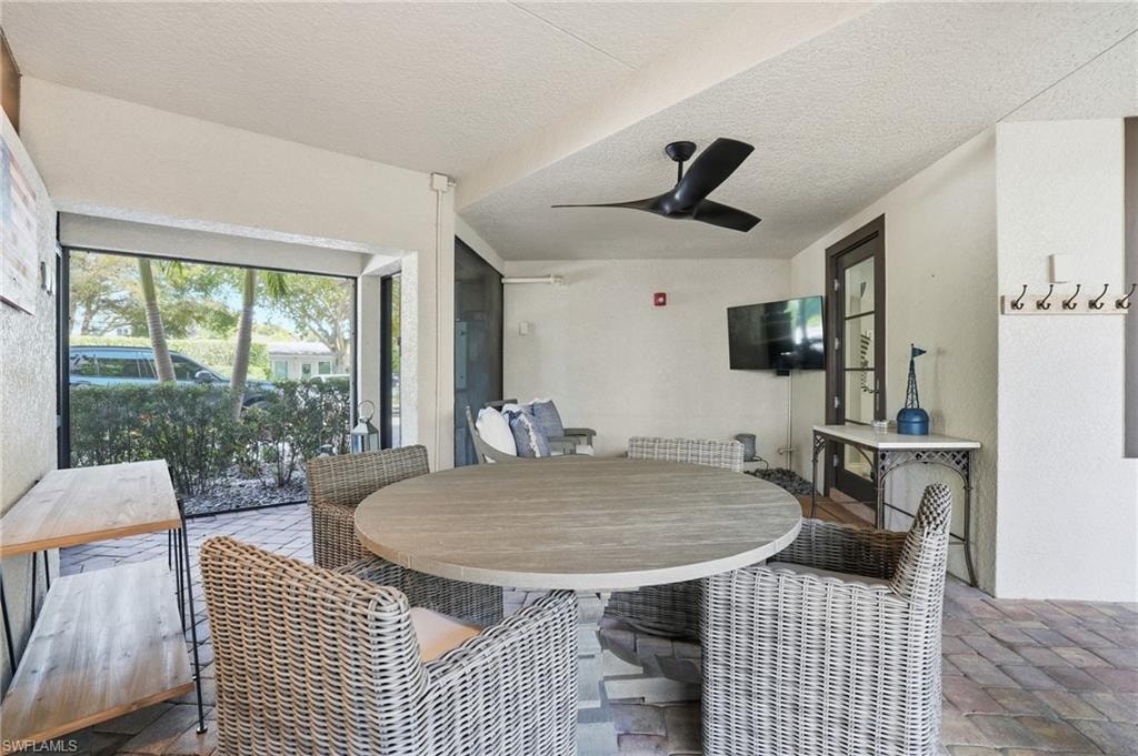 View of patio / terrace featuring outdoor dining space, a ceiling fan, and a sunroom
