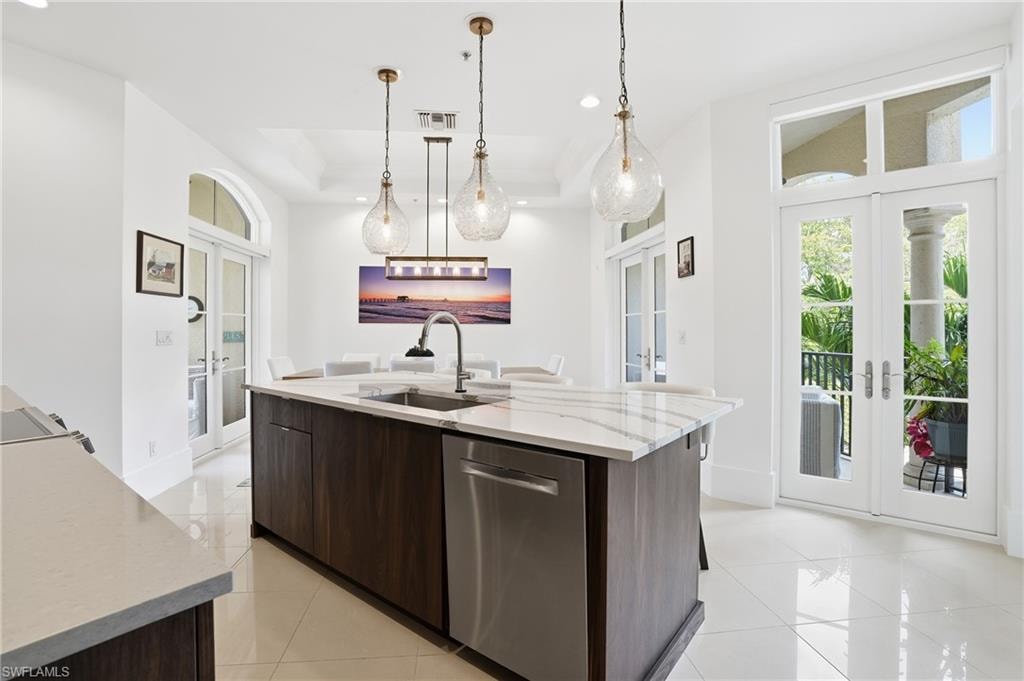 Kitchen with french doors, dark wood finish cabinets, modern cabinets, light stone counters, and dishwasher
