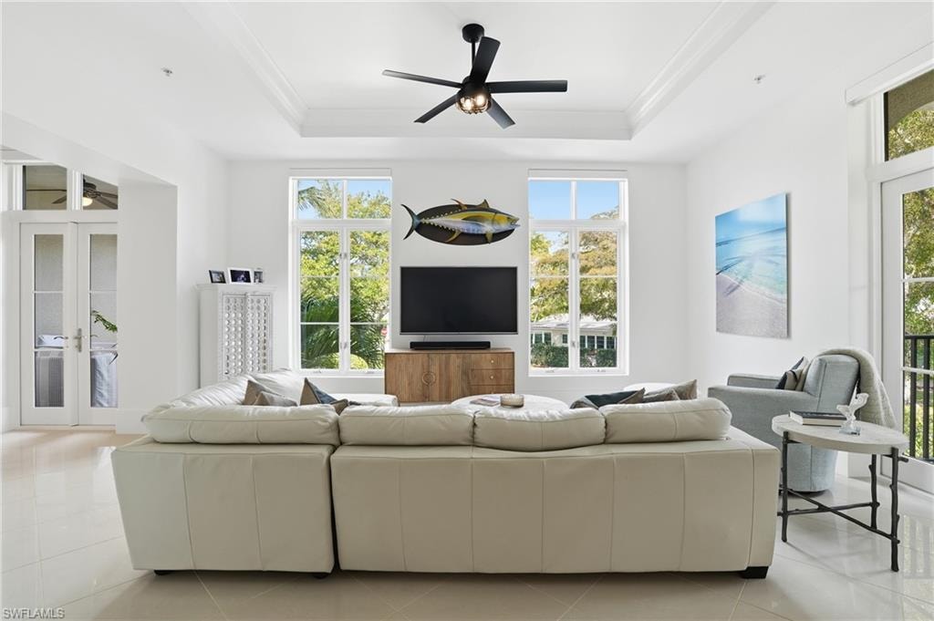 Living room with a ceiling fan, light tile patterned floors, and french doors