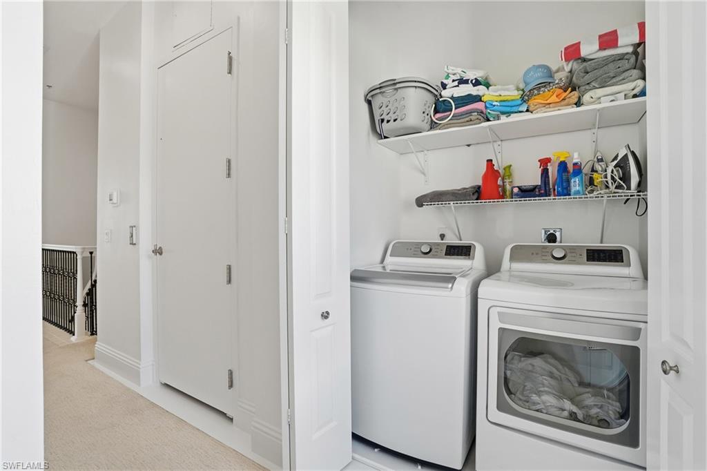 Laundry area featuring light colored carpet and separate washer and dryer