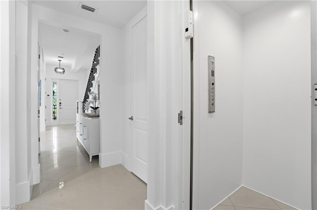 Corridor with light tile patterned flooring and elevator