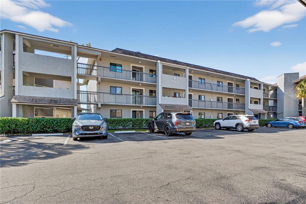 View of apartment building / complex featuring uncovered parking
