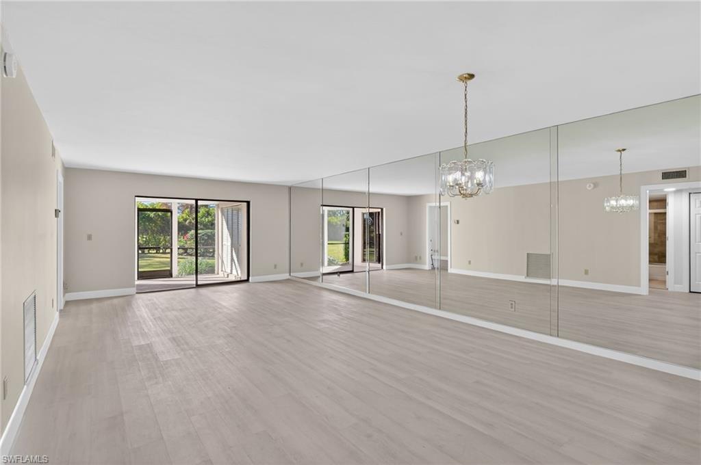 Mirrored living/dining room featuring hanging lights and light vinyl-type flooring