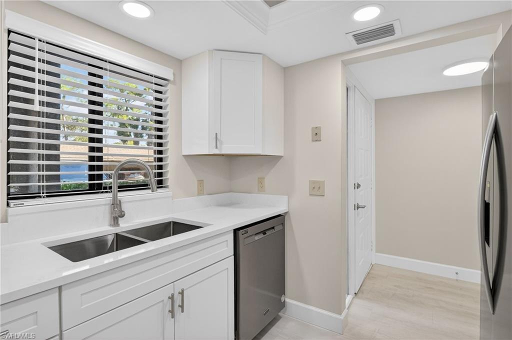 Kitchen with white cabinetry, stainless steel appliances, light stone countertops, recessed lighting, and light wood finished floors