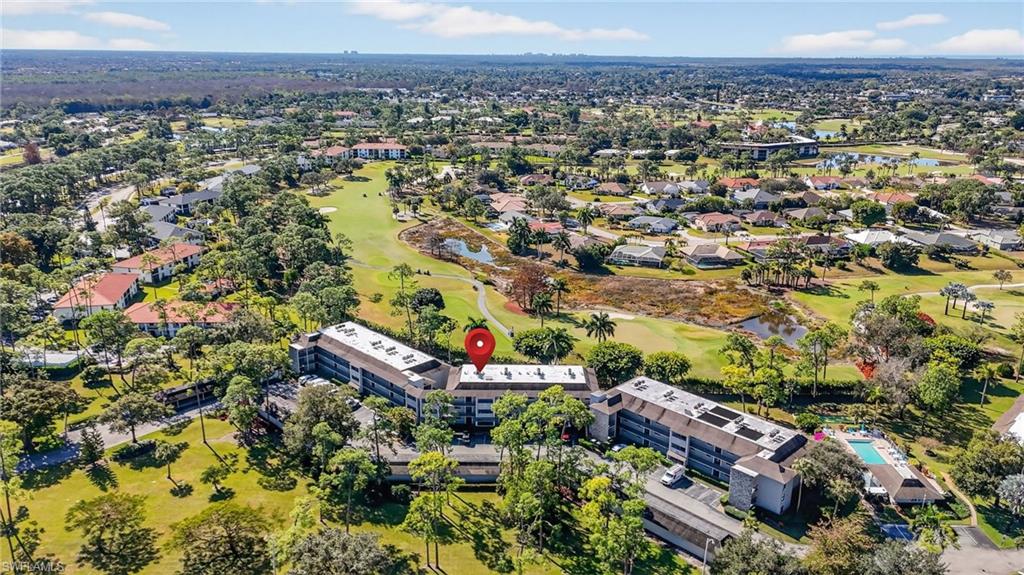 Aerial view of property and surrounding area with a golf club and a nearby body of water