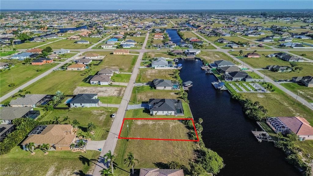 Aerial perspective of suburban area with property boundaries highlighted and a nearby body of water