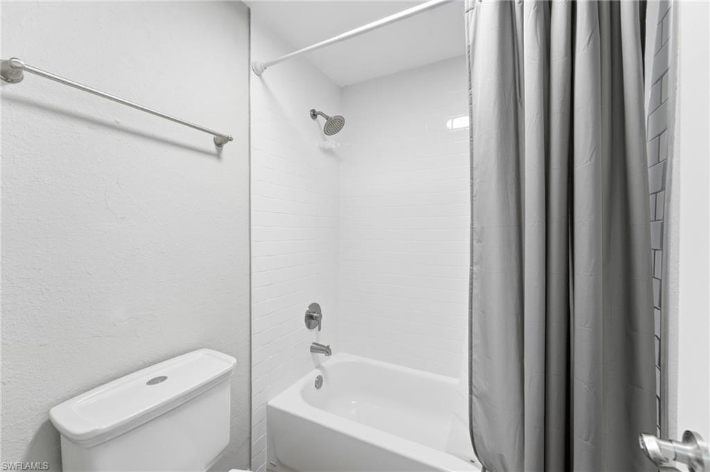 Full bathroom with shower / tub combo with curtain and toilet