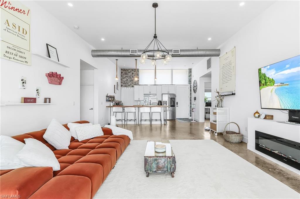 Living area with a chandelier, concrete floors, and a high ceiling