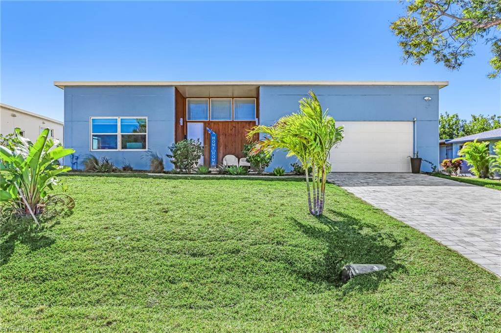 View of front of house featuring a front lawn, stucco siding, and decorative driveway