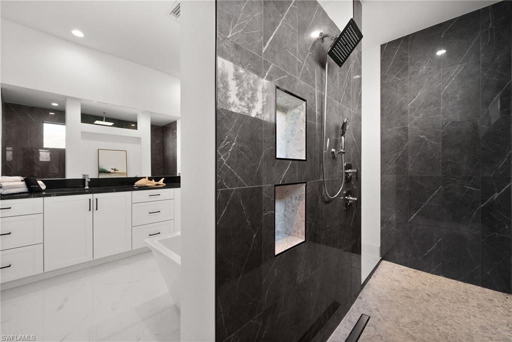 Bathroom with a marble finish shower, vanity, light marble finish floors, and a soaking tub