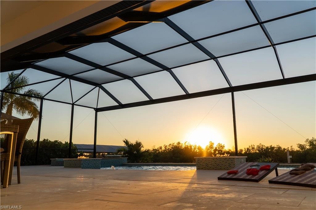 Pool at dusk featuring a lanai and a patio area