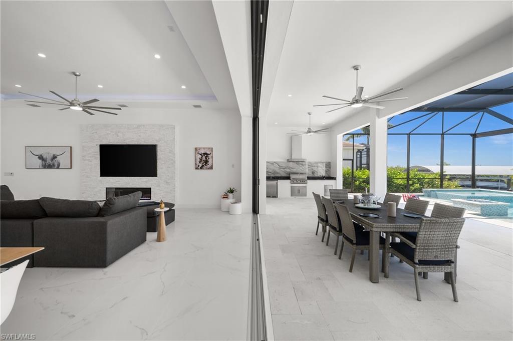 Dining space with a ceiling fan, a sunroom, recessed lighting, a fireplace, and a raised ceiling