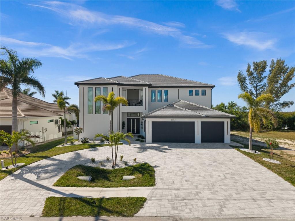 View of front facade featuring driveway, a garage, a balcony, a front lawn, and stucco siding