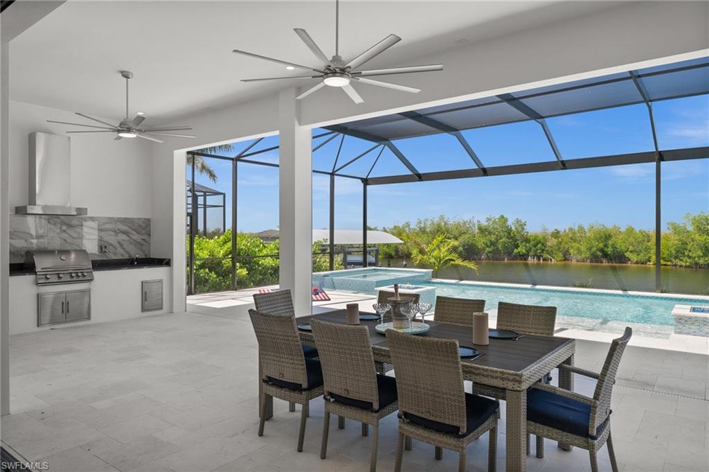 View of patio featuring an outdoor kitchen / dining area, glass enclosure, a ceiling fan, a pool with connected hot tub, and a sunroom