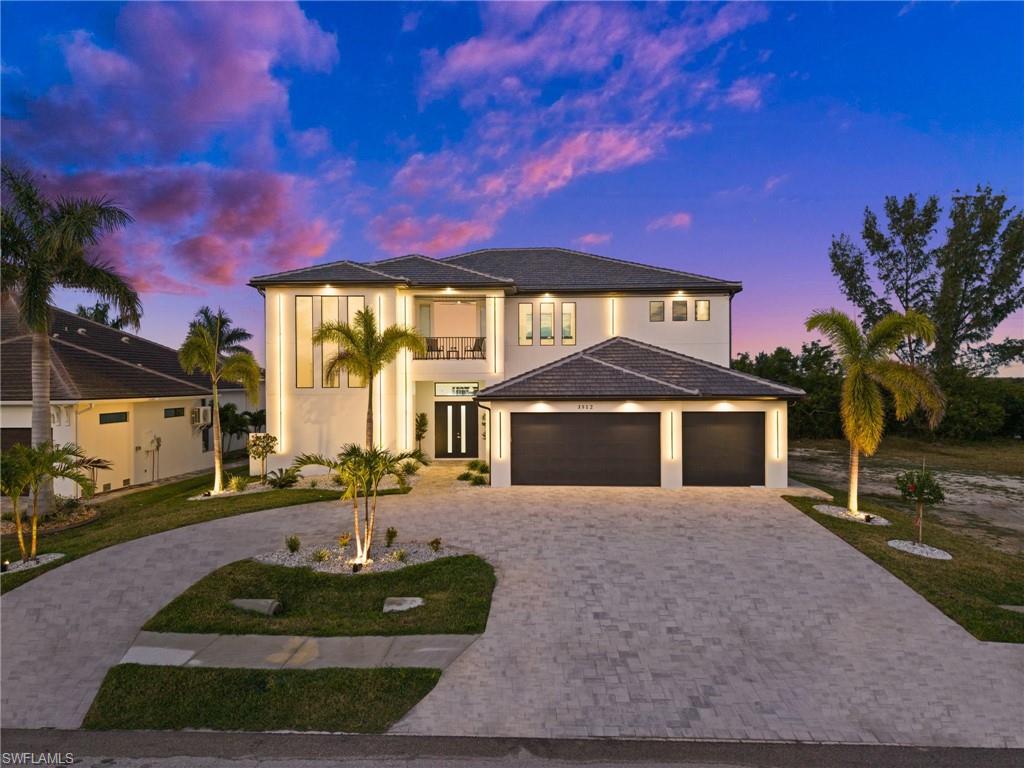 View of front of property featuring curved driveway, stucco siding, an attached garage, and a front lawn
