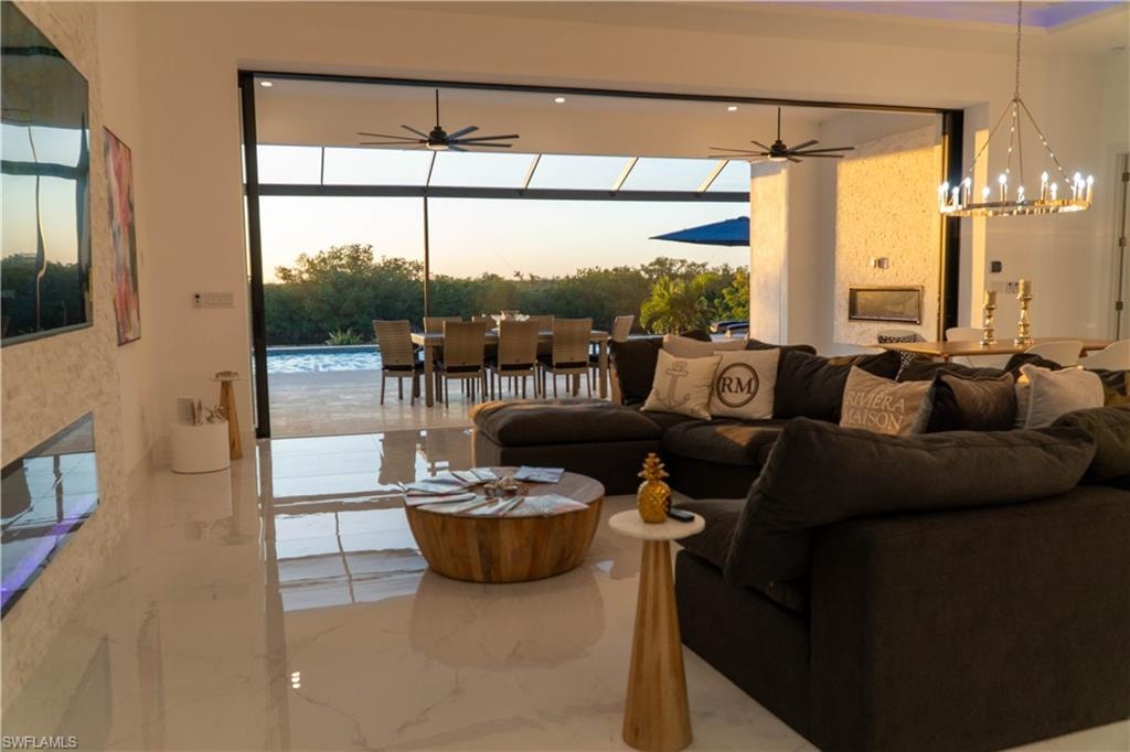 Living room with a chandelier, a fireplace, healthy amount of natural light, and ceiling fan