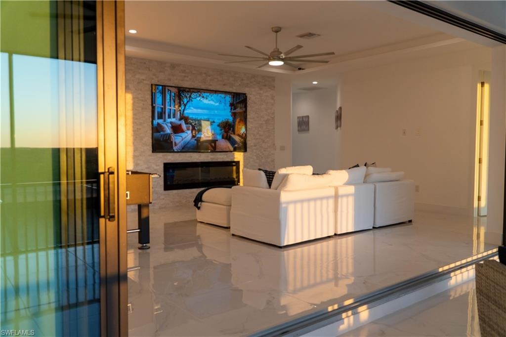 Cinema featuring marble tiled flooring, a ceiling fan, recessed lighting, and a glass covered fireplace