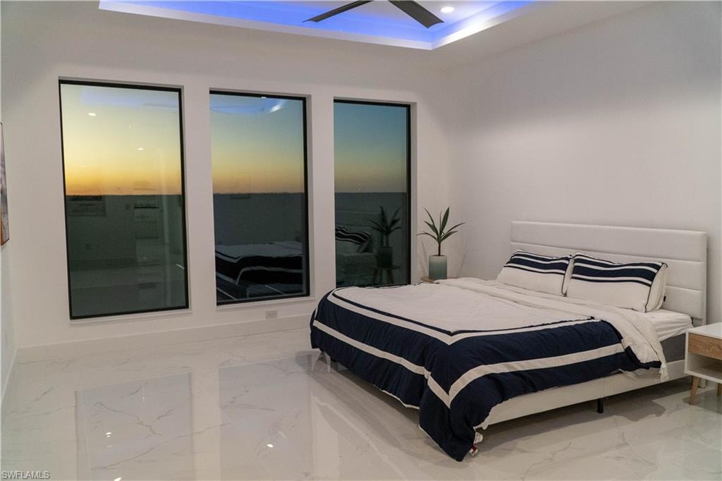 Bedroom featuring a raised ceiling, marble tiled floors, and recessed lighting