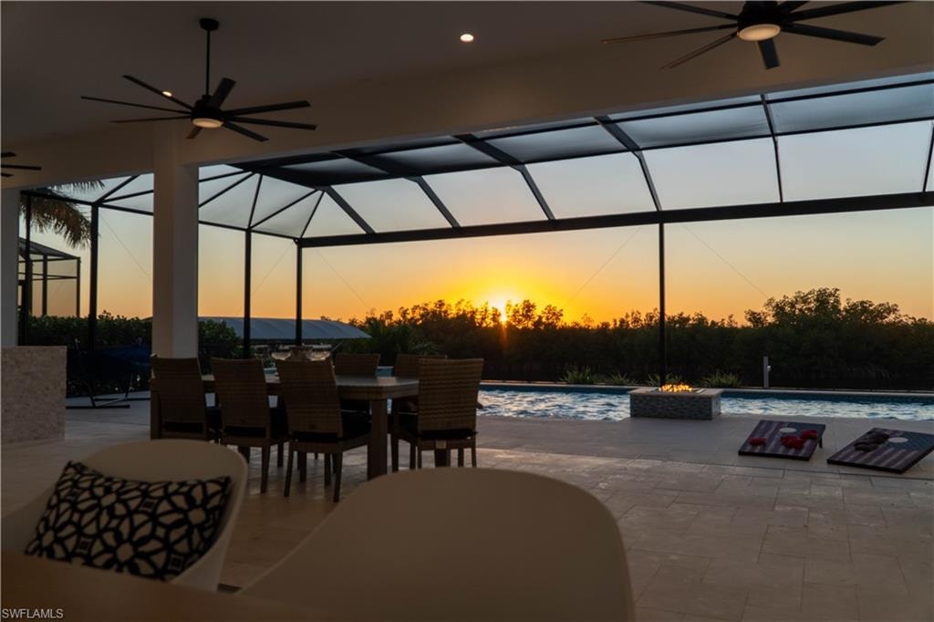 Patio terrace at dusk featuring ceiling fan, a lanai, a patio, and outdoor dining space