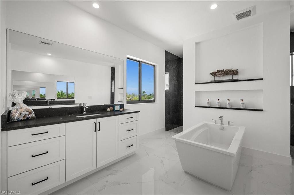Full bath featuring healthy amount of natural light, a freestanding tub, walk in shower, vanity, and recessed lighting
