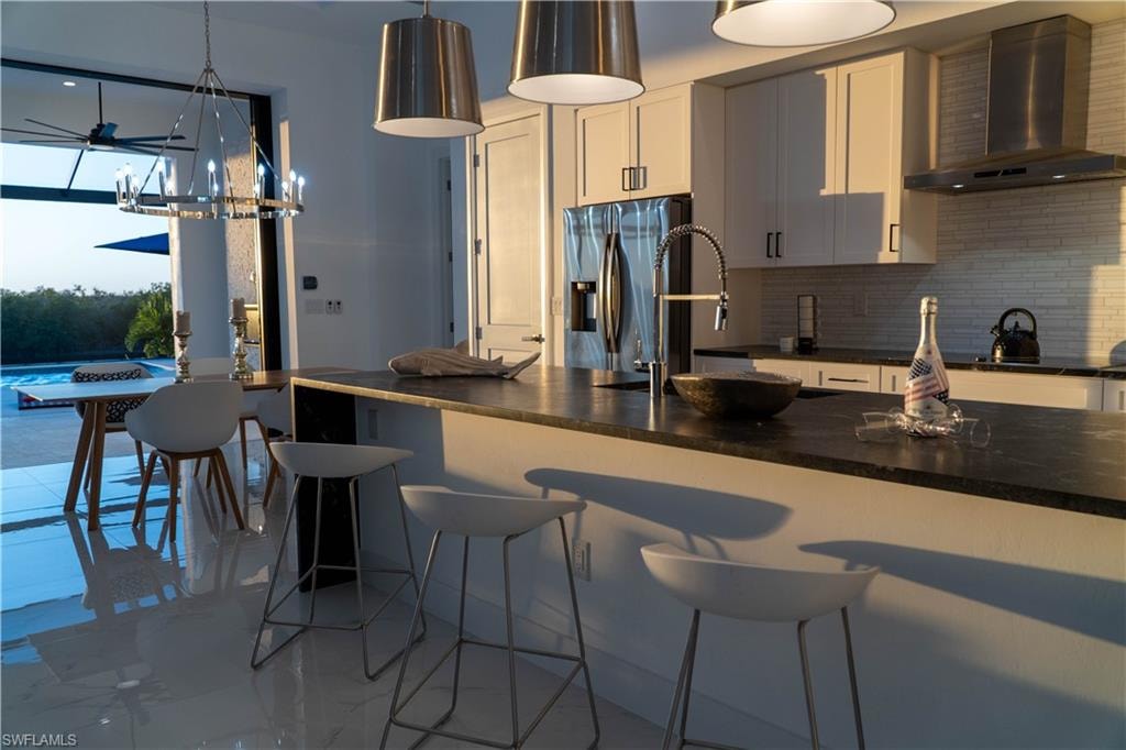 Kitchen featuring a breakfast bar area, stainless steel fridge with ice dispenser, and pendant lighting