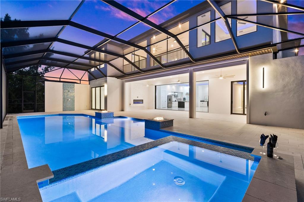 Pool at dusk with a pool with connected hot tub, a lanai, and a patio