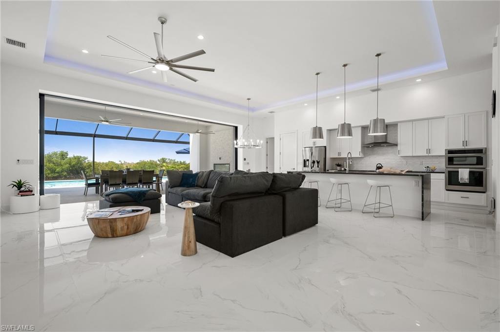 Living room featuring a sunroom, ceiling fan, a raised ceiling, and recessed lighting