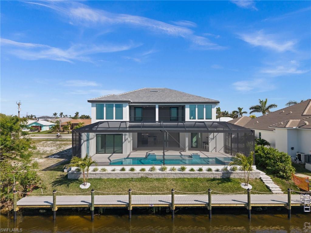 Back of property with a sunroom, a water view, a lanai, and a patio