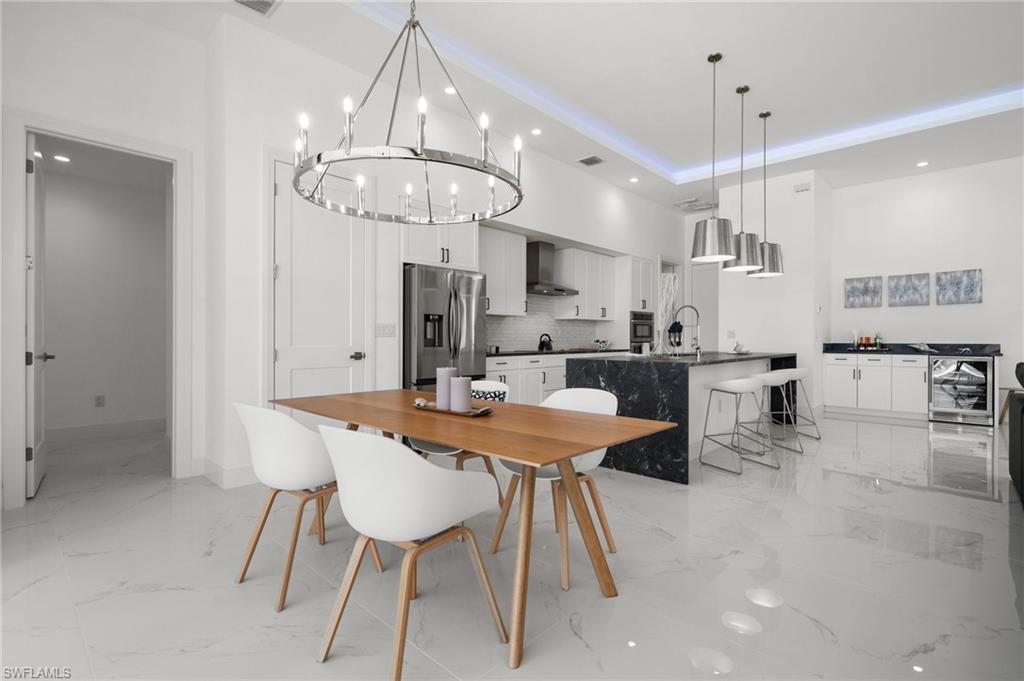 Dining room featuring hanging lights, a raised ceiling, and light marble finish flooring