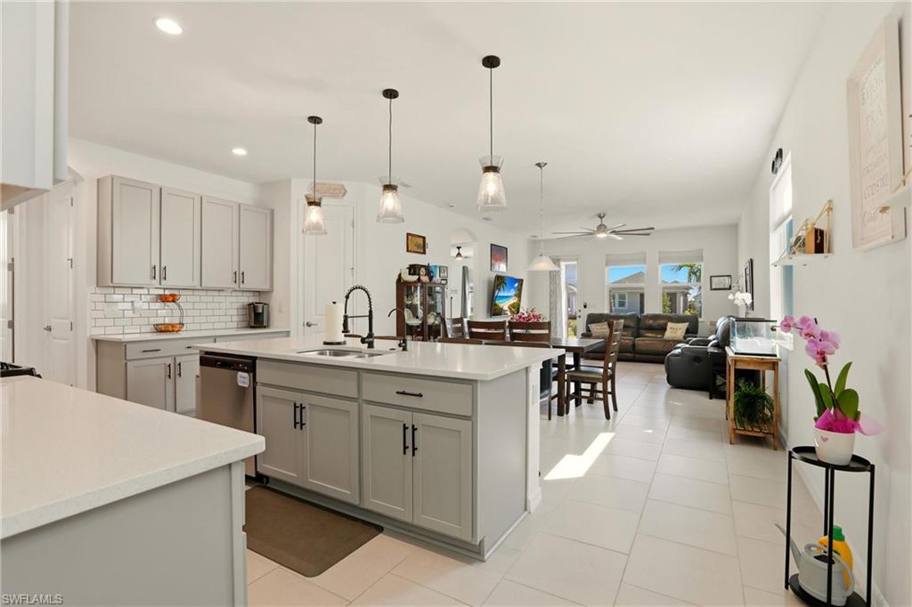 Kitchen with gray cabinets, pendant lighting, a center island with sink, and open floor plan