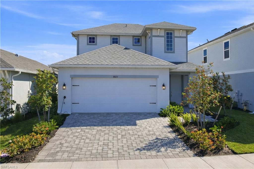 View of front of house with a shingled roof, decorative driveway, a garage, a front yard, and stucco siding