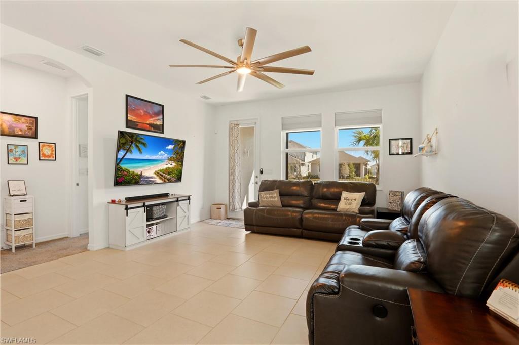 Living room featuring arched walkways, ceiling fan, and light tile patterned flooring