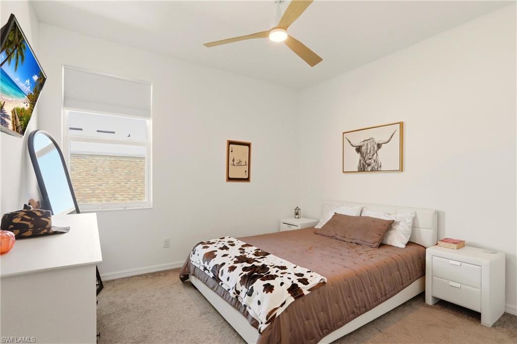 Bedroom with light colored carpet and a ceiling fan