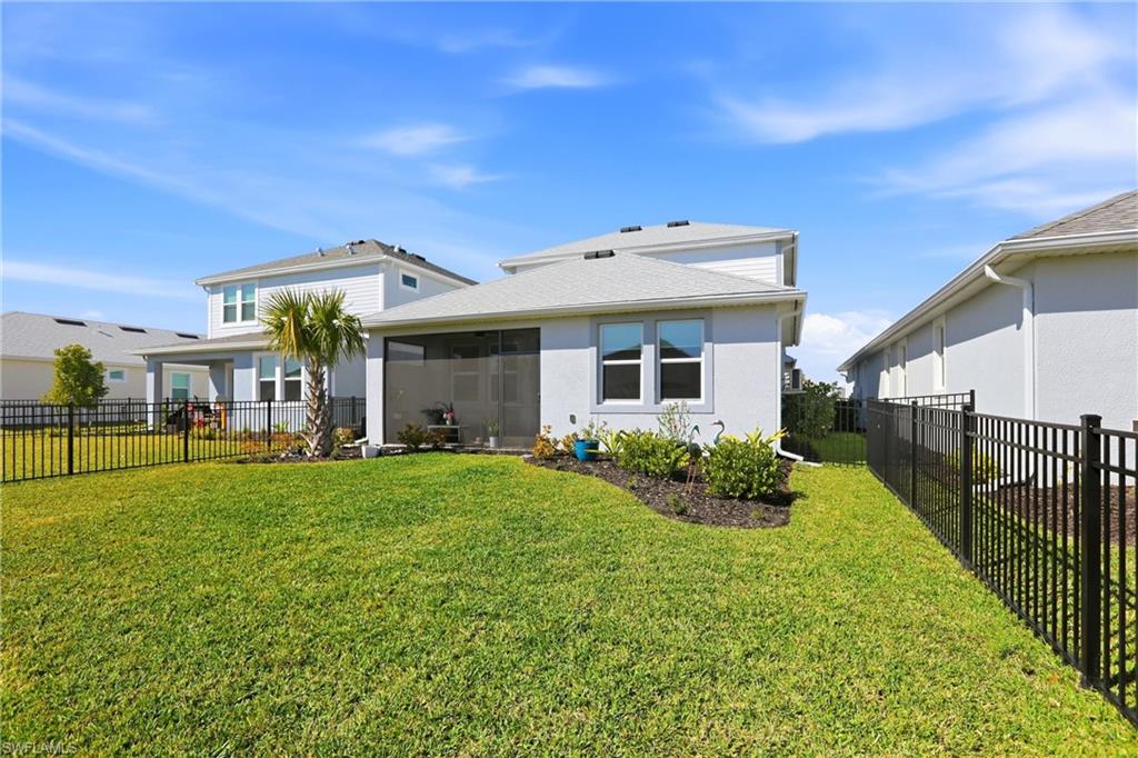 Back of house featuring a fenced backyard, stucco siding, and a sunroom