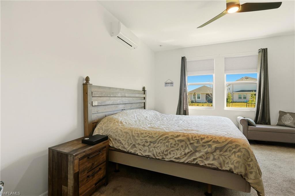 Carpeted bedroom with a mini split for heating / cooling and ceiling fan
