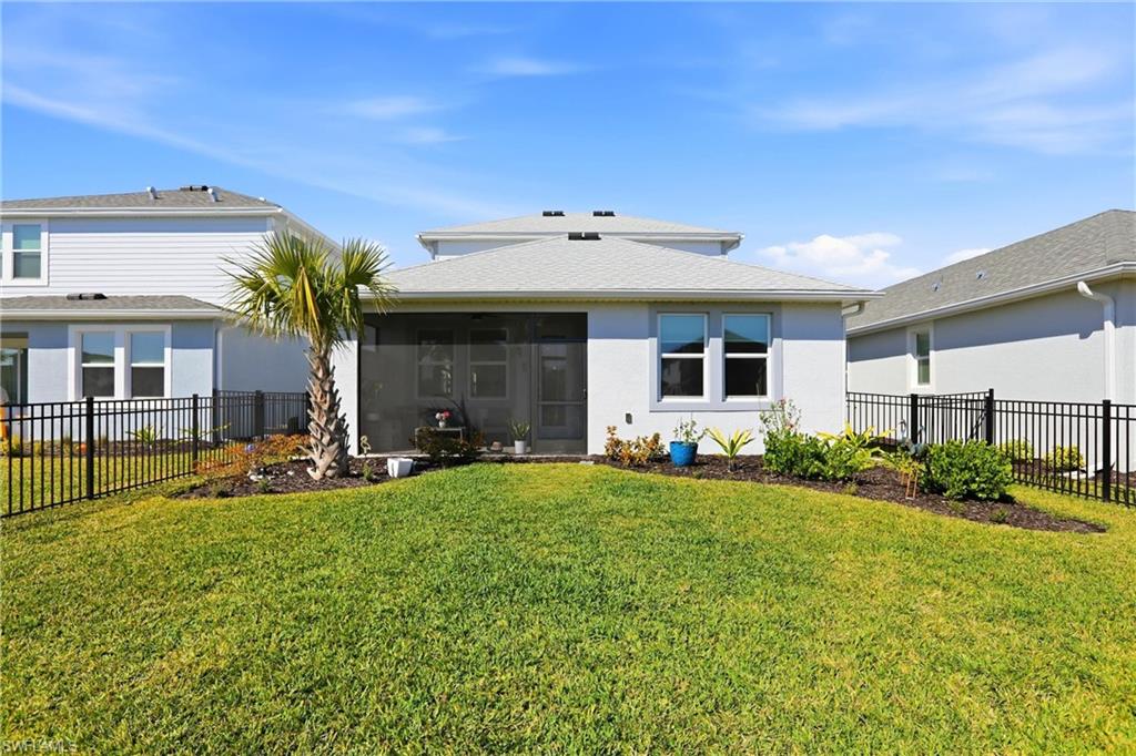 Back of property featuring a fenced backyard, a sunroom, and stucco siding