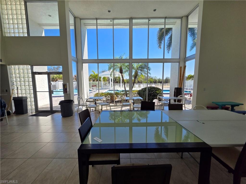 Dining area with a high ceiling, expansive windows, and tile patterned floors