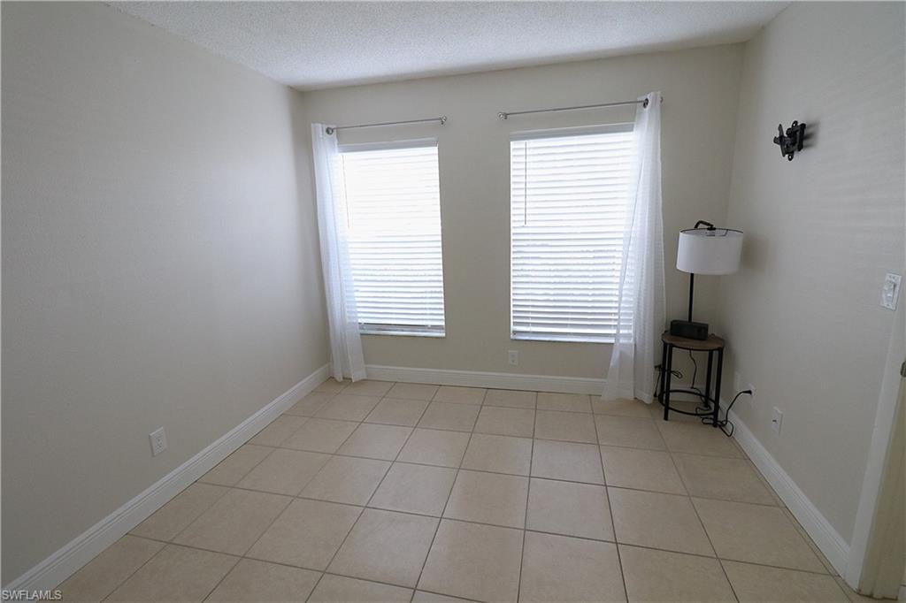 Empty room with a textured ceiling and light tile patterned flooring