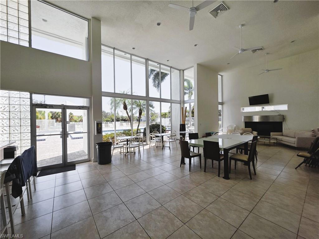 Dining area featuring tile patterned floors, healthy amount of natural light, expansive windows, and a high textured ceiling