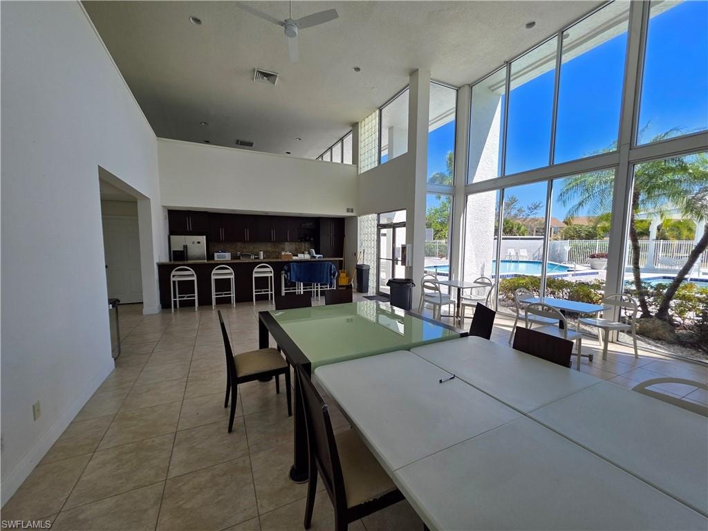 Dining space featuring a high ceiling, ceiling fan, light tile patterned flooring, and expansive windows