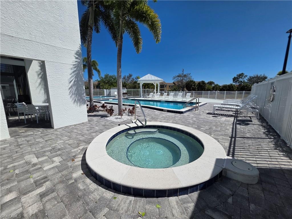 Community pool featuring a patio, a gazebo, and a hot tub